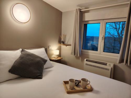a bedroom with a bed with two cups on it at Maison d'hôtes Beauregard in Donneville