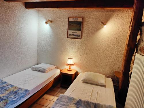 two beds in a room with a lamp on a table at La Butinerie in Prévenchères