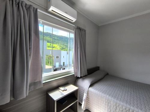 a small bedroom with a bed and a window at Hotel Bergozza in Rio do Sul