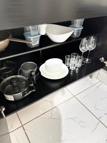 a kitchen with a black counter with dishes and glasses at Studio Confortável no Centro com Garagem in Araquari
