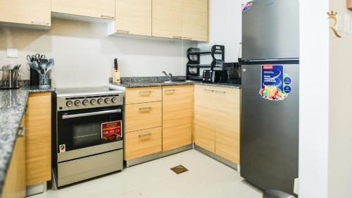a kitchen with wooden cabinets and a stainless steel refrigerator at Azure Marina 1BR - Elegant Chic Haven in Abu Dhabi