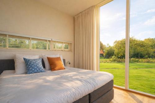a bedroom with a large bed and a large window at Weidesuite bij Leeuwarden. Natuur en 11stedenwater in Weidum