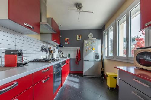 a kitchen with red cabinets and a white refrigerator at La Belle Escale - Maison proche gare et d'Orléans in Fleury-les-Aubrais