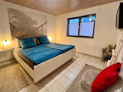 a bedroom with a bed with blue sheets and a window at Barrierefreies Ferienhaus mit Garten bei Köln in Hürth