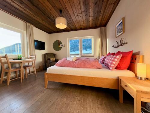 a bedroom with a bed with red pillows and a table at Boutique Hotel Alpenhof in Sankt Martin am Tennengebirge