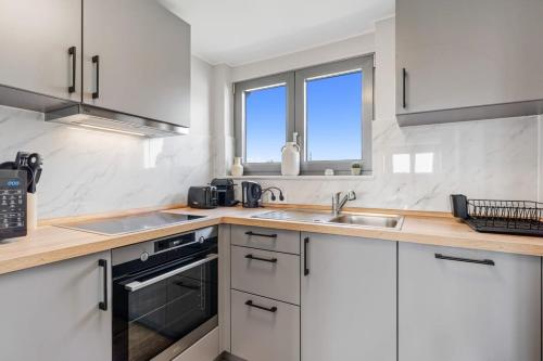 a kitchen with white cabinets and a sink at Modern Limpertsberg Studio Near City Center in Luxembourg
