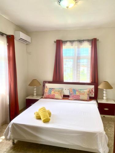 a bedroom with a large white bed with red curtains at Appartement first floor in Trou aux Biches