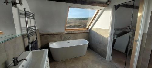 a bathroom with a tub and a sink and a window at School House in Reeth
