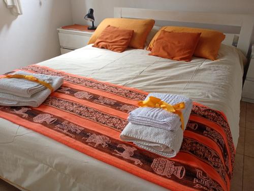 a bed with orange and white towels on it at Arcadia in Merlo