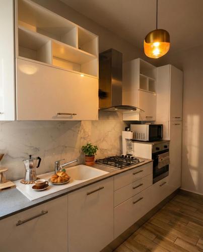 a kitchen with white cabinets and a sink and a stove at Oasi Domese Appartamento Centrale in Domodossola