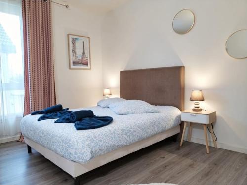 a bedroom with a bed with blue clothes on it at Sibiti, charmant 2 pièces à 20 minutes de Paris in Le Blanc-Mesnil
