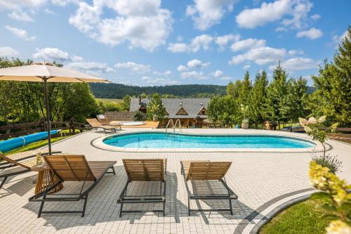 a swimming pool with chairs and an umbrella at Gościniec Rabe - Agro&SPA in Ustrzyki Dolne