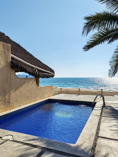 a swimming pool next to a beach with the ocean at Suite en área turística de Manzanillo con club de playa in Manzanillo