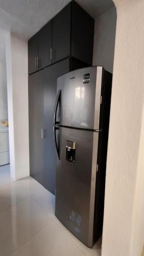 a stainless steel refrigerator in a kitchen with black cabinets at Suite en área turística de Manzanillo con club de playa in Manzanillo
