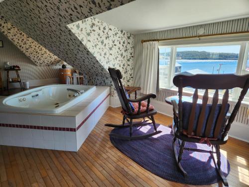 a bathroom with a tub and two rocking chairs at Louisbourg Harbour Inn in Louisbourg