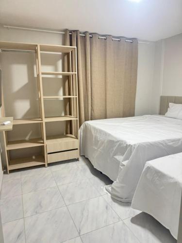 a bedroom with two beds and a book shelf at Via do Sol flats in Amontada