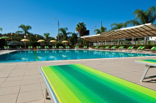 a large swimming pool with chairs and umbrellas at Residence Atlante in Leporano