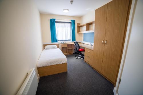 a bedroom with a bed and a desk with a computer at University of Essex - Southend Campus in Southend-on-Sea