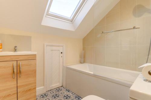 a bathroom with a sink and a bath tub and a window at 4 Bed in Sheringham oc-m28357 in Sheringham