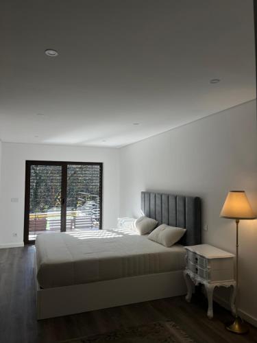 a white bedroom with a large bed and a window at Little Haven Houses Lousada in Lousada