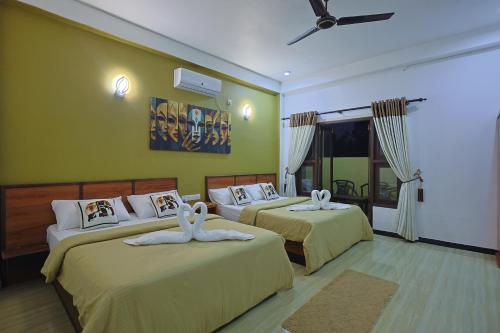 two beds in a room with green walls at Canal's Edge in Negombo