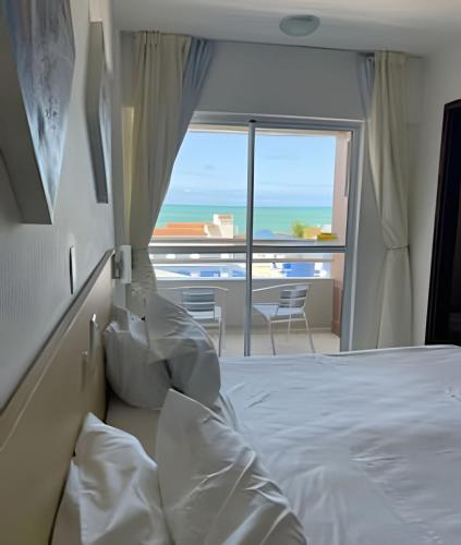 a bedroom with a bed and a view of the ocean at Flat no Terrazzo perto do mar in Natal