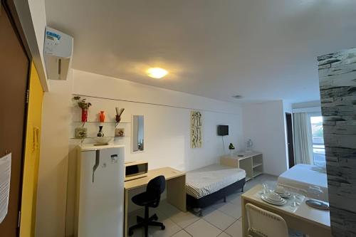 a small room with a desk and a bed and a refrigerator at Flat no Terrazzo perto do mar in Natal