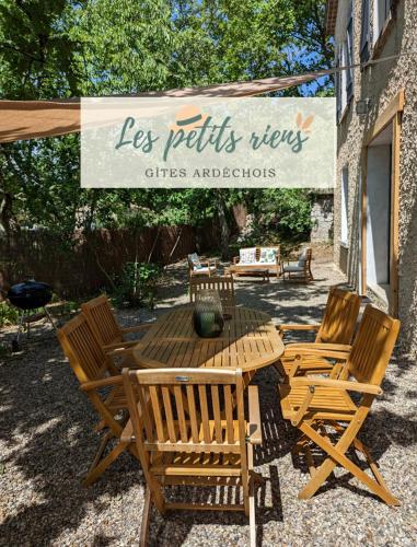 a wooden table and chairs with a sign that reads les petits views cities applications at Gîte Le Petit rien du Bas in Balazuc