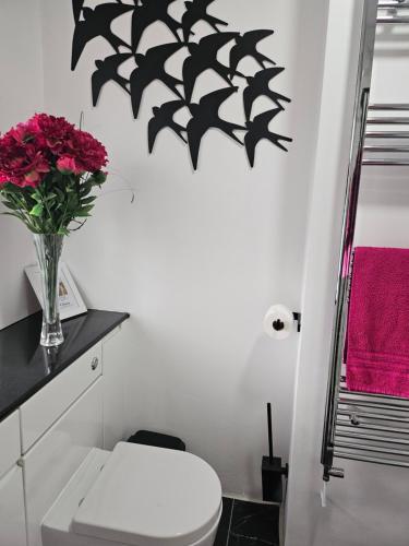 a bathroom with a toilet and a vase of flowers on the wall at Shalom, in Saundersfoot, near the sea in Saundersfoot