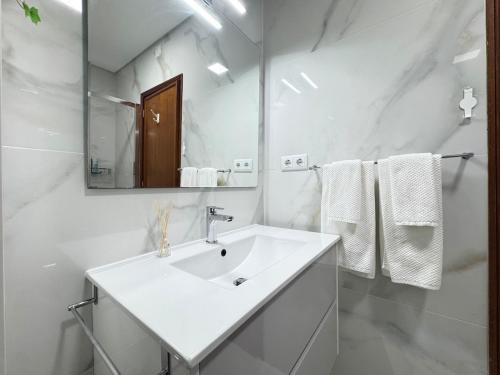 a white bathroom with a sink and a mirror at Refugio do Atlântico in Marinhas