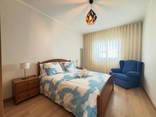 a bedroom with a bed and a blue chair at Refugio do Atlântico in Marinhas