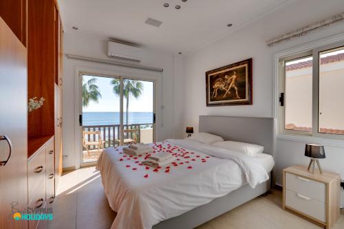 a bedroom with a bed with red roses on it at Beachfront Villa Carpe Diem in Mor Menekshe