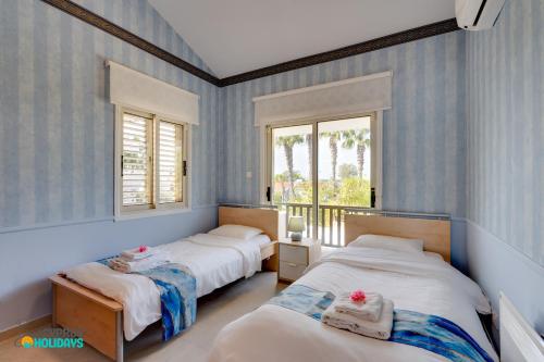 two beds in a room with blue striped walls at Beachfront Villa Carpe Diem in Mor Menekshe