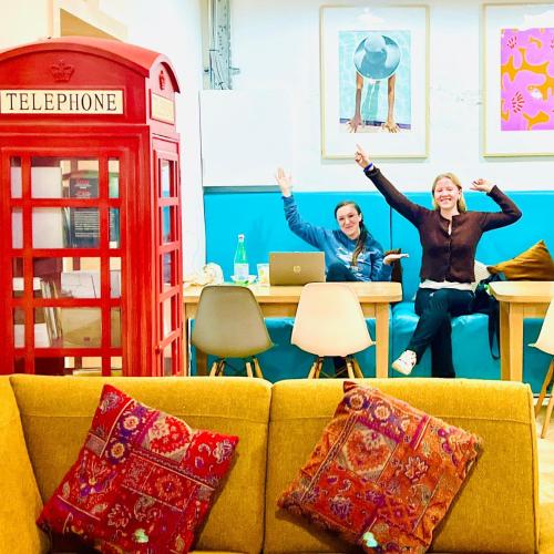 two people sitting in a room with a telephone booth at Follow the Sun Boutique Hostel - Pool, Breakfast & Sea Views in St. Julianʼs
