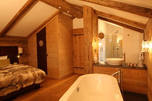 a bathroom with a bath tub and a bed at Maierl-Alm & Maierl-Chalets in Kirchberg in Tirol