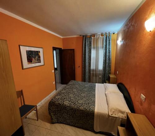 a bedroom with a bed in a room with orange walls at Albergo Il Pescatore in Trevi