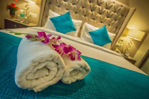 a towel with flowers on it sitting on a bed at Sarovar Portico- Jalandhar in Jalandhar