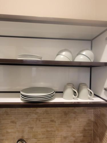 a shelf with plates and cups and dishes on it at Cozy, Tiny, Retreat Studio in a prime location in Abu Dhabi