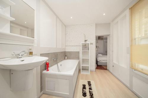 a white bathroom with a sink and a bath tub at SoHo Elegant Apartment - West End 102 sq meters in London
