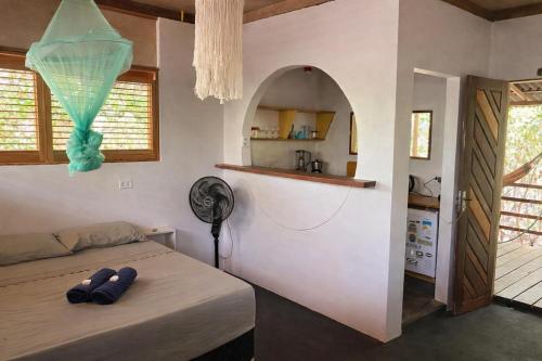a room with a bed and a kitchen with a fan at Plancton House Atins in Atins