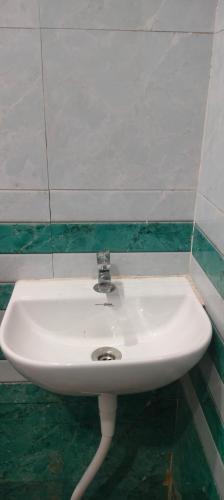 a white sink in a bathroom with green tiles at Hotel Dharma palace in Prayagraj