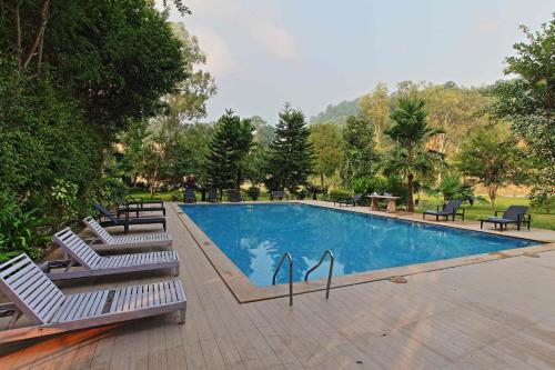 a swimming pool with two lounge chairs next to it at Riverside By Aahma in Garjia