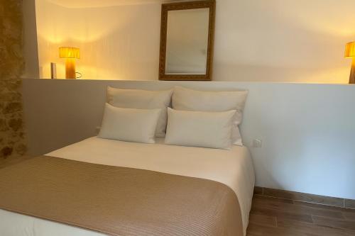 a bed with white pillows and a mirror on the wall at Le Moulin de Lauve in Saint-Hilaire-les-Courbes