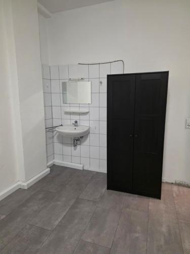 a bathroom with a sink and a black door at modernes & einfaches übernachten in Bruchsal