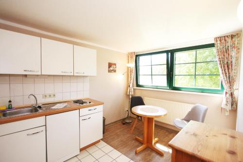 a kitchen with white cabinets and a table and a window at Pension Forstfuhrmannshof in Markgrafenheide
