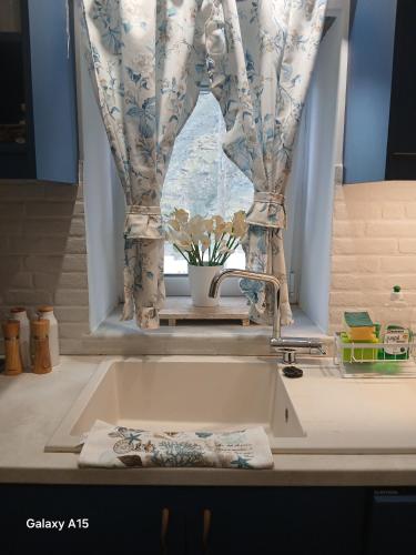 a kitchen sink with a window with a curtain at Dipotamata House SynetI in Andros