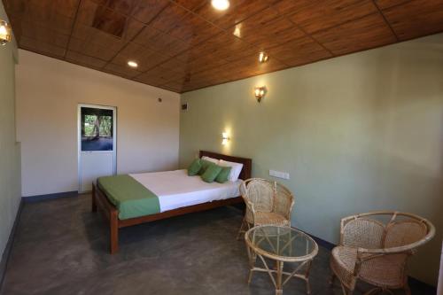 a bedroom with a bed and chairs in a room at Green Heaven in Dickwella