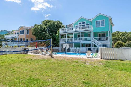 a house with a volleyball net in a yard at Family Tradition - Duck Landing, Oceanside, 130 Yds to Beach, Pool, Hot Tub, Tiki Bar in Duck