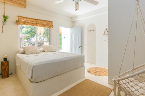 a white bedroom with a bed and a window at Kibayo Cabarete Boutique Hotel in Cabarete
