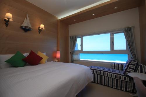 a bedroom with a bed and a window with the ocean at Hotel Bayview in Dahan